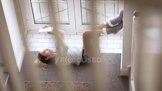 Женщина с цифровой планшет у окна дома — стоковое фото