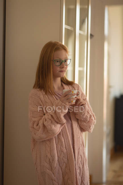 Задумчивая девушка пьет кофе дома — стоковое фото