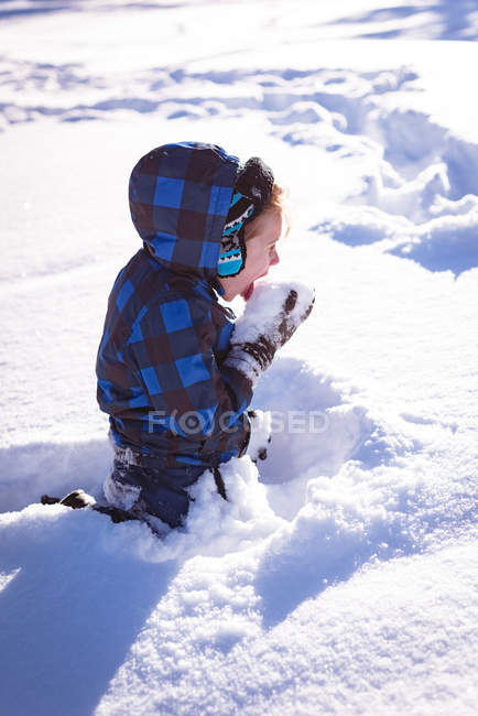 Mignon garçon lécher neige pendant hiver — Photo de stock