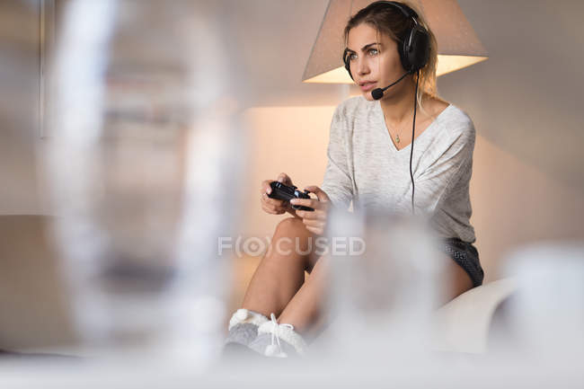 Mulher jogando videogame com fone de ouvido na sala de estar em casa — Fotografia de Stock