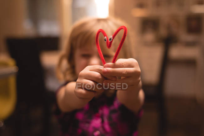 Girl holding heart shape decoration at home — Stock Photo