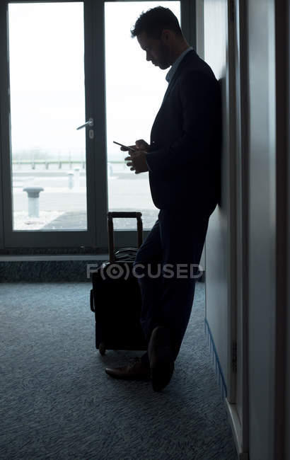 Homme d'affaires utilisant le téléphone portable dans la chambre d'hôtel — Photo de stock