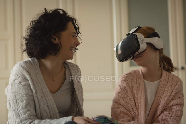 Mutter lächelt, während Tochter Virtual-Reality-Headset zu Hause benutzt — Stockfoto