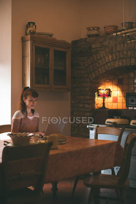 Smiling woman using laptop at home — Stock Photo
