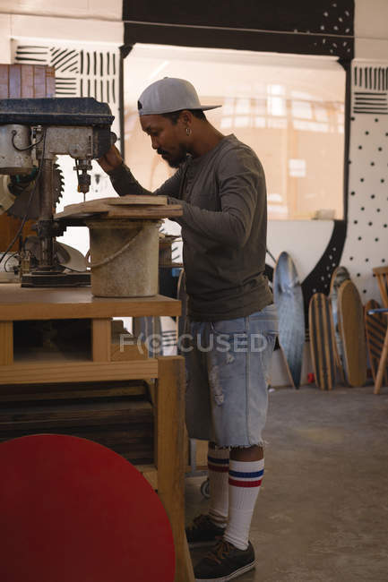Mann benutzt Radialbohrmaschine in Skateboard-Werkstatt — Stockfoto