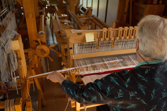 Rear view of senior woman weaving silk at shop — Stock Photo