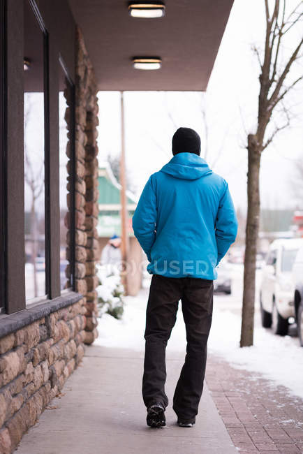 Uomo che cammina con le mani in tasca sul marciapiede durante l'inverno . — Foto stock
