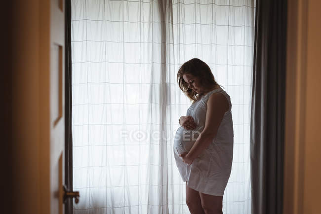 Pregnant woman looking down towards her belly and holding it — Stock Photo