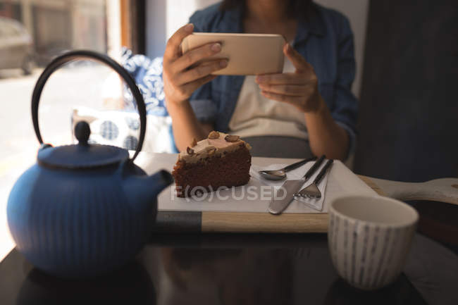 Pregnant woman taking photo of pastry with mobile phone at cafe — Stock Photo