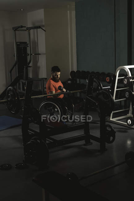 Homme handicapé en fauteuil roulant travaillant avec haltère dans la salle de gym — Photo de stock