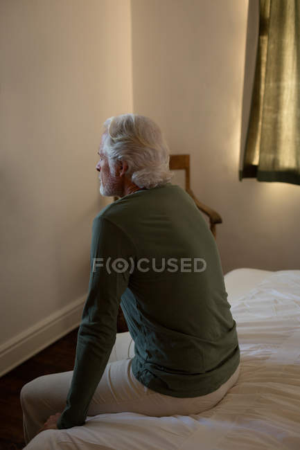 Thoughtful senior man relaxing in bedroom at home — Stock Photo