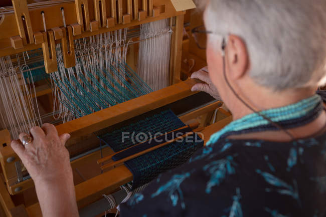 Close-up of senior woman weaving silk at shop — Stock Photo