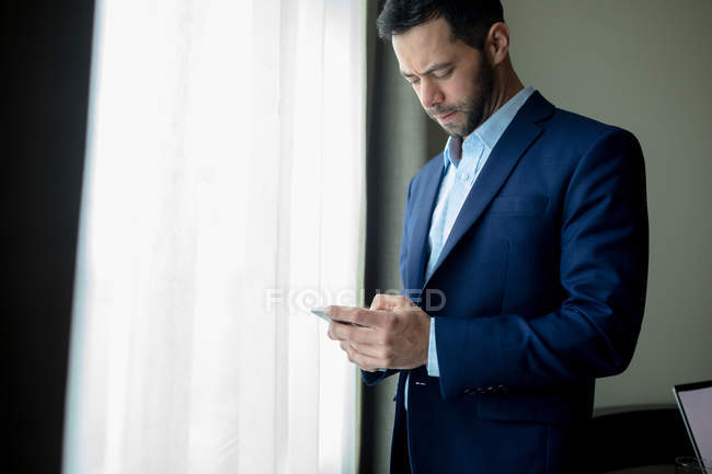 Бізнесмен, використовуючи мобільний телефон в готельному номері — стокове фото