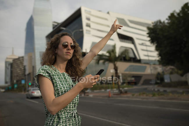 Mulher bonita saudando para passeio com um telefone celular na mão — Fotografia de Stock