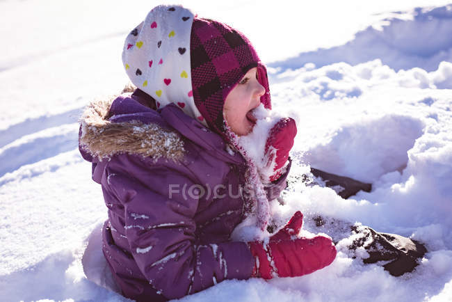 Menina bonito lambendo neve durante o inverno — Fotografia de Stock