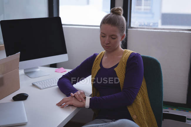 Блондинка керівник використовує смарт-годинник в офісі — стокове фото