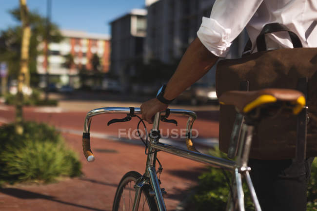 Partie médiane de l'homme d'affaires marchant avec son vélo dans les locaux du bureau — Photo de stock