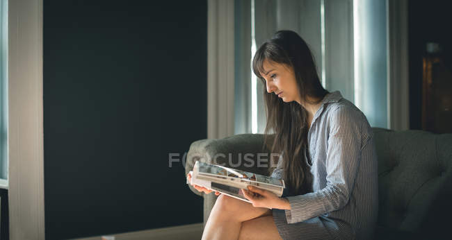 Mulher ler revista na sala de estar em casa — Fotografia de Stock