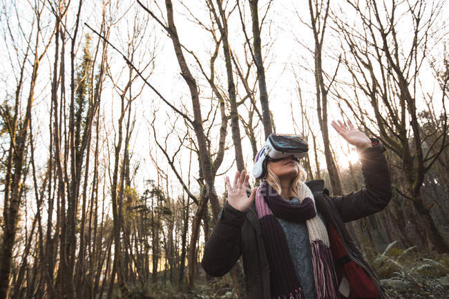 Жінка за допомогою віртуальної реальності гарнітуру в лісі, низький кут зору. — Stock Photo