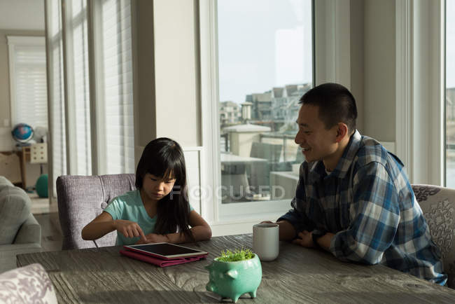 Girl using digital tablet with her father at home — Stock Photo