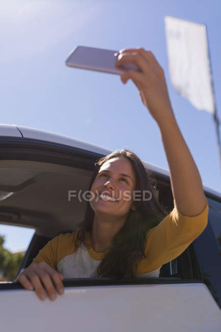 Beautiful woman taking selfie with mobile phone in a car — Stock Photo
