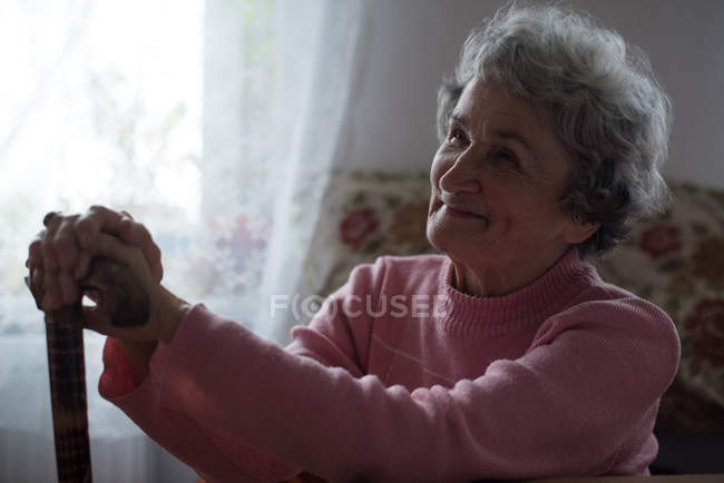 Продуманий старший жінка посміхаючись вдома — стокове фото