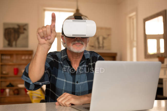 Старший чоловік за допомогою віртуальної реальності гарнітура з ноутбуком кухні в домашніх умовах — стокове фото