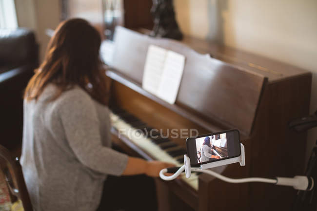Hermosa vlogger femenina tocando el piano en casa - foto de stock