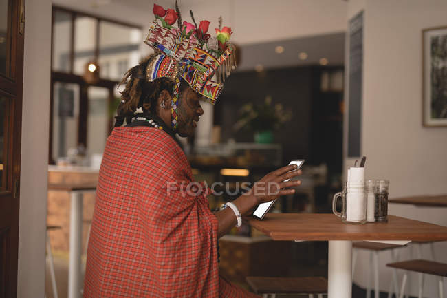 Hombre masai en ropa tradicional usando tableta digital en el restaurante - foto de stock