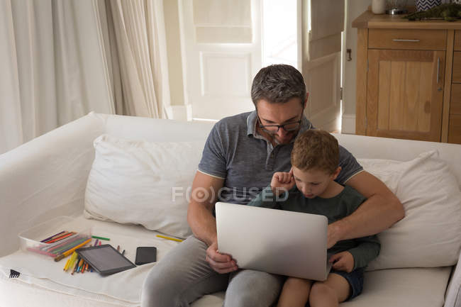 Отец и сын используют ноутбук в гостиной на дому — стоковое фото