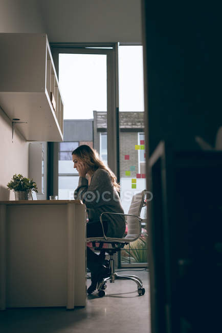 Жінка-виконавця, що працює на ноутбуці в офісі — стокове фото