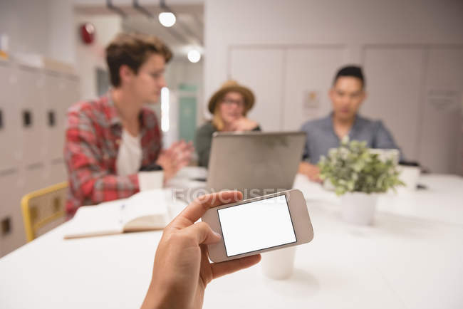Executive using mobile phone and colleague working background in creative office — Stock Photo