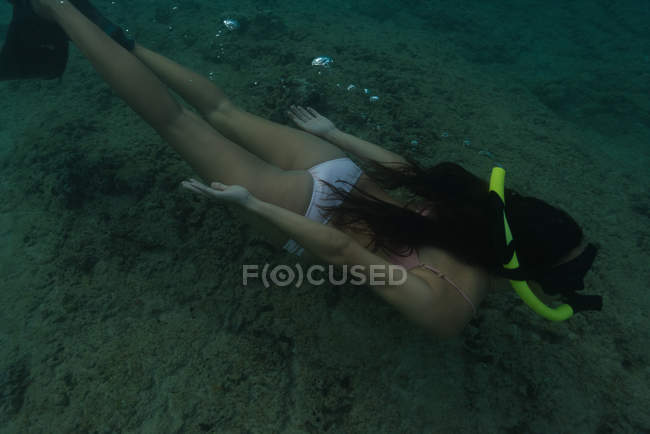 Женщина ныряющая с аквалангом под водой в морской воде — стоковое фото