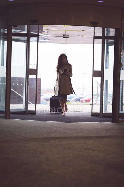 Mulher de negócios sofisticada usando telefone celular ao chegar no hotel — Fotografia de Stock