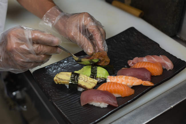 Primer plano del chef organizando comida de mar en una bandeja - foto de stock