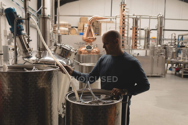 Worker filling alcoholic drink in drum at factory — Stock Photo