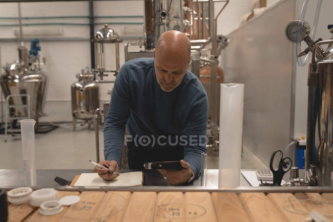 Працівник використовує цифровий планшет під час написання на папері на заводі — стокове фото
