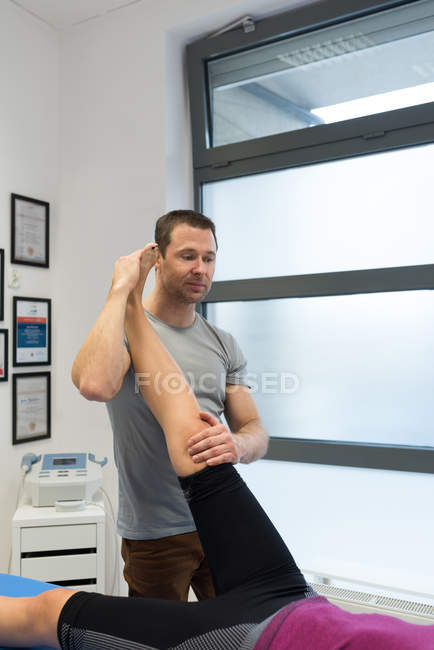 Fisioterapista che fa un massaggio alle gambe alla donna in clinica — Foto stock