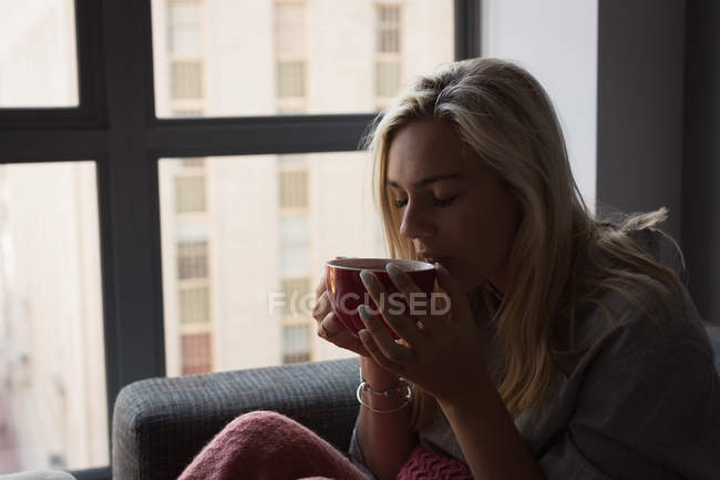 Woman having coffee in living room at home — Stock Photo