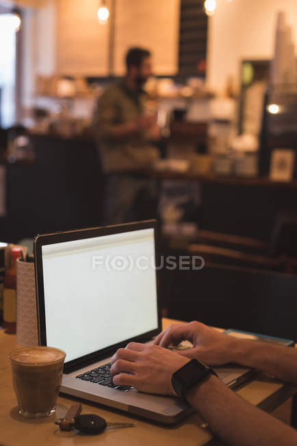 Primer plano de la mano masculina usando el ordenador portátil en la cafetería . - foto de stock