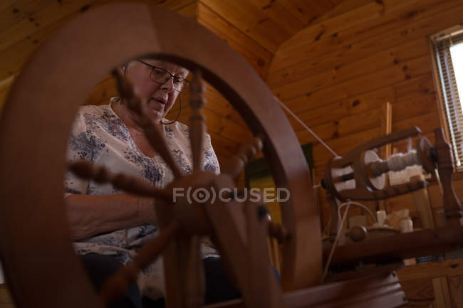 Mujer mayor activa tejiendo seda en la tienda - foto de stock