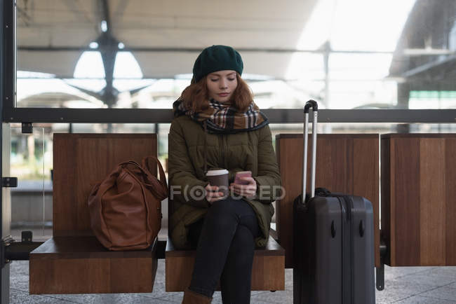 Женщина с чашкой кофе с помощью мобильного телефона в зале ожидания — стоковое фото