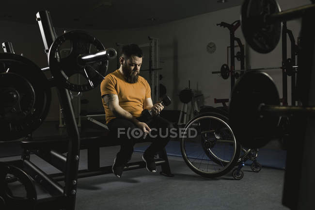 Hombre discapacitado haciendo ejercicio con mancuerna en el gimnasio - foto de stock