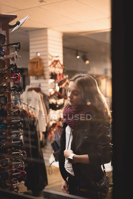 Schönes Mädchen wählt Sonnenbrille vom Display in Einkaufszentrum — Stockfoto