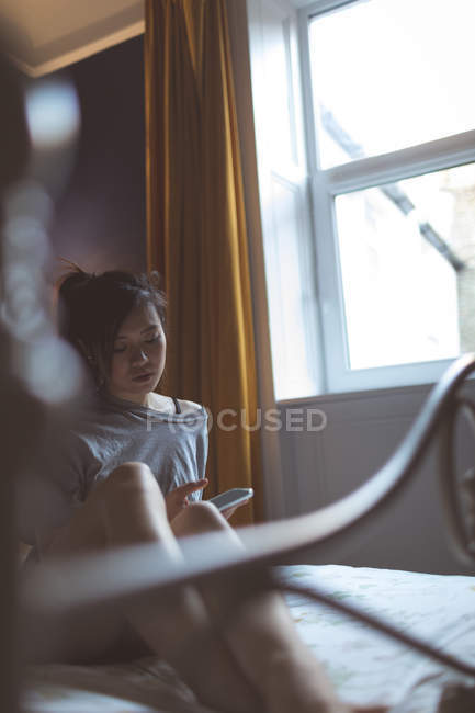 Woman using mobile phone in bedroom at home — Stock Photo