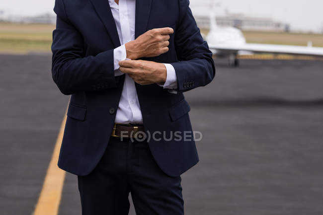 Mid section of businessman buttoning his shirt sleeves on a runaway — Stock Photo