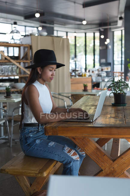 Chica adolescente atenta usando el ordenador portátil en el restaurante - foto de stock