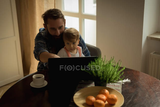 Padre tomando café mientras juega con su hijo en casa - foto de stock