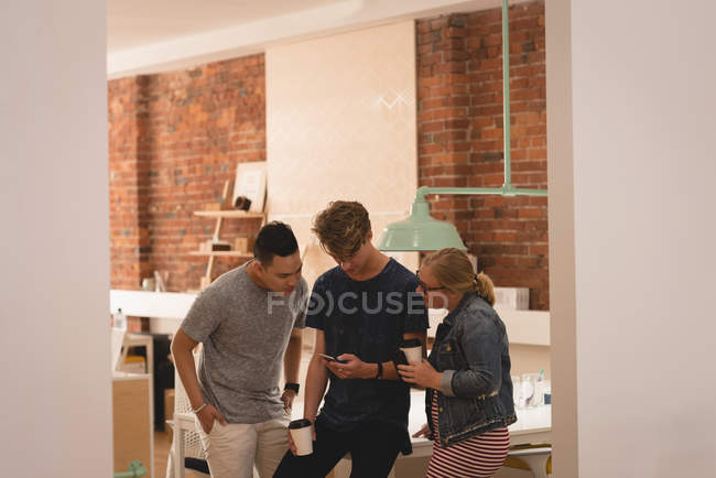Executivos olhando para o telefone celular no escritório criativo — Fotografia de Stock
