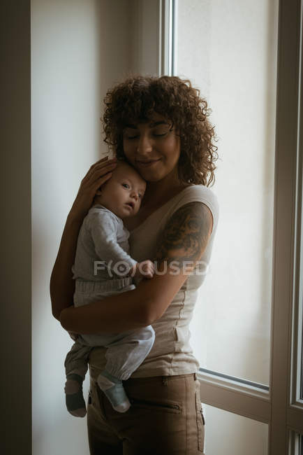Zärtliche Mutter umarmt ihr Baby zu Hause — Stockfoto